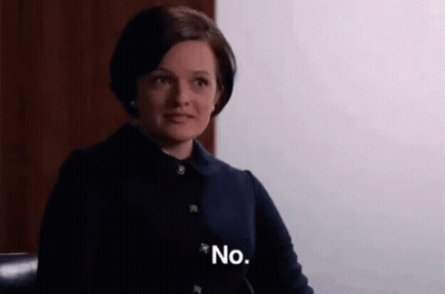 A Woman In A Black Jacket Is Sitting In A Chair And Saying No . GIF