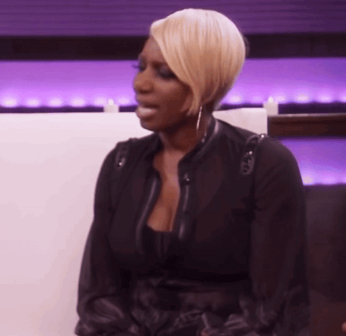 A Woman In A Black Jacket Is Sitting On A White Couch GIF