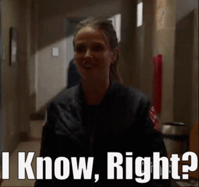 A Woman In A Black Jacket Is Standing In A Hallway And Says I Know Right . GIF