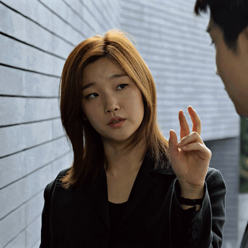 A Woman In A Black Jacket Talks To A Man In A Suit GIF