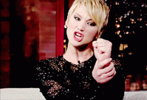 A Woman In A Black Lace Dress Is Making A Funny Face GIF