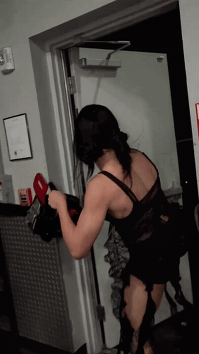 A Woman In A Black Lace Top Is Standing In A Doorway GIF