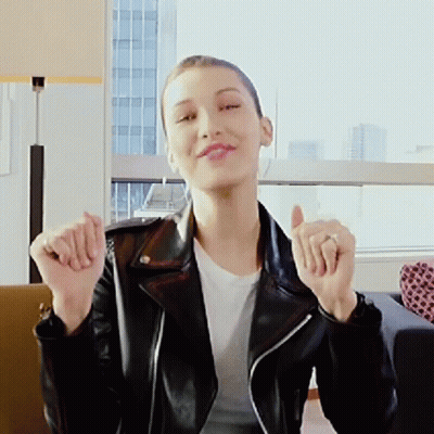 A Woman In A Black Leather Jacket Is Giving A Thumbs Up Sign GIF