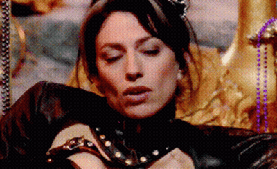 A Woman In A Black Leather Outfit Is Laying On A Throne With Her Eyes Closed GIF