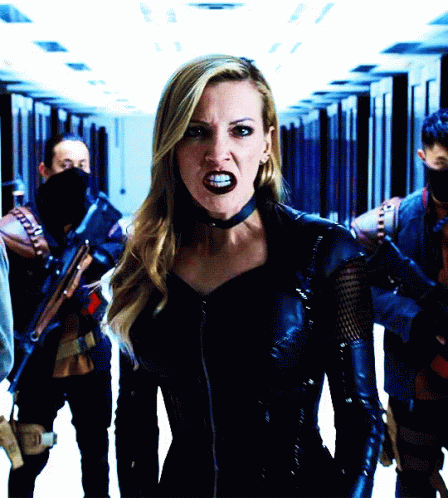 A Woman In A Black Leather Outfit Stands In A Hallway GIF