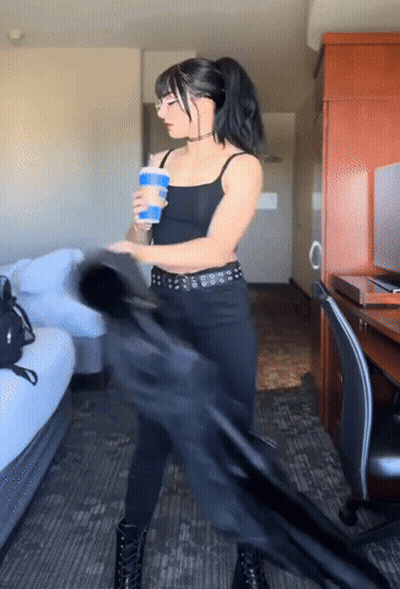 A Woman In A Black Outfit Is Holding A Blue Cup GIF