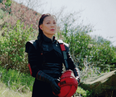 A Woman In A Black Outfit Is Holding A Red Helmet That Says Kthx GIF