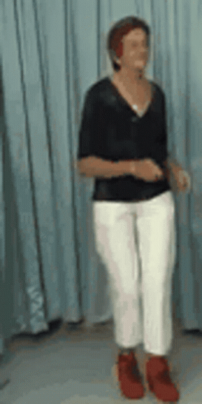 A Woman In A Black Shirt And White Pants Is Dancing GIF