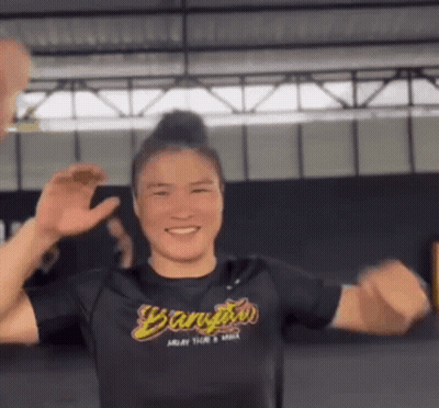 A Woman In A Black Shirt Is Dancing In A Gym . GIF