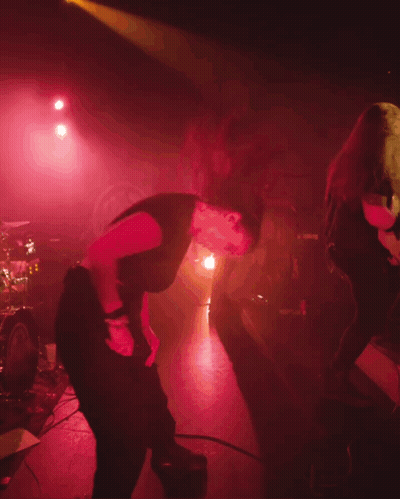 A Woman In A Black Shirt Is Dancing On Stage GIF