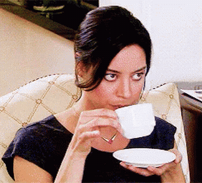 A Woman In A Black Shirt Is Drinking From A White Cup GIF