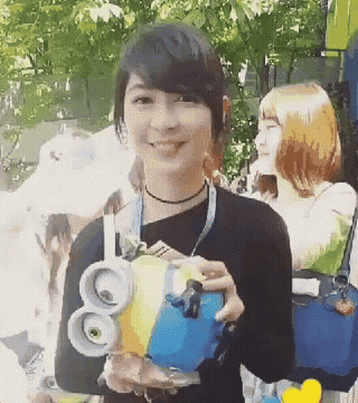 A Woman In A Black Shirt Is Holding A Blue And Yellow Object With The Number 80 On It GIF