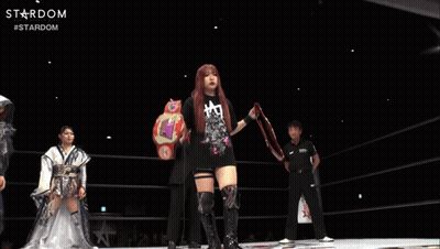 A Woman In A Black Shirt Is Holding A Wrestling Belt With The Word Stardom On It GIF