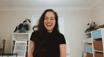 A Woman In A Black Shirt Is Laughing In A Room With The Name Elaniezanetti On The Bottom GIF