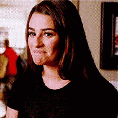 A Woman In A Black Shirt Is Making A Funny Face And Looking At The Camera . GIF