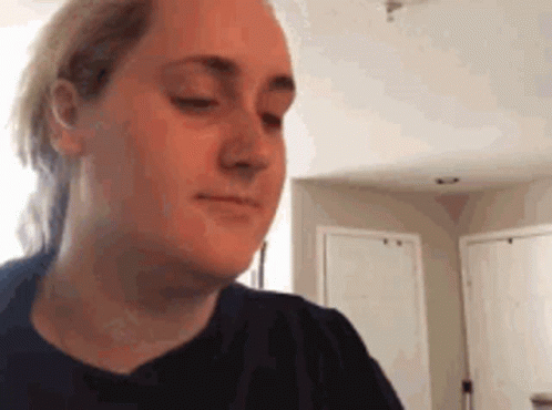 A Woman In A Black Shirt Is Making A Funny Face In A Kitchen . GIF