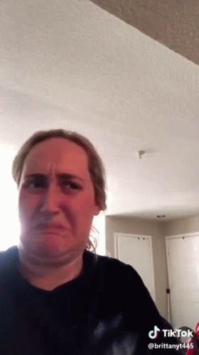 A Woman In A Black Shirt Is Making A Funny Face In A Tiktok Video . GIF