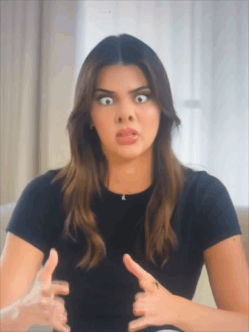A Woman In A Black Shirt Is Making A Funny Face With Her Hands GIF
