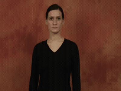 A Woman In A Black Shirt Is Making A Hand Gesture With Her Hands . GIF