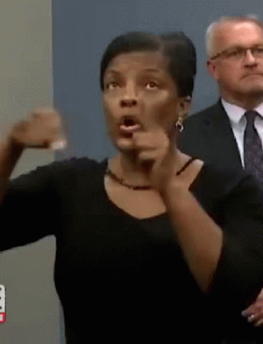 A Woman In A Black Shirt Is Pointing At Something GIF