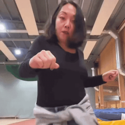 A Woman In A Black Shirt Is Pointing Her Finger At The Camera . GIF