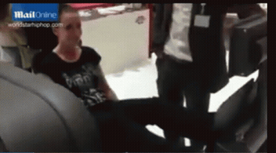 A Woman In A Black Shirt Is Sitting In The Back Seat Of A Car In Front Of A Blue Sign That Says Mail Online GIF