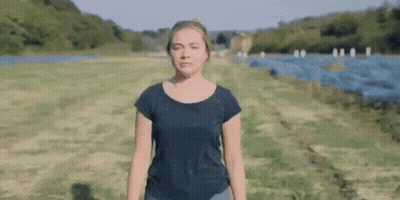 A Woman In A Black Shirt Is Standing In A Field . GIF