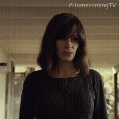 A Woman In A Black Shirt Is Standing In A Hallway With #Homecoming Tv Written Above Her GIF