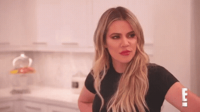 A Woman In A Black Shirt Is Standing In A Kitchen With Her Arms Crossed . GIF