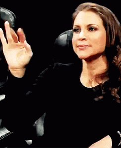 A Woman In A Black Shirt Is Waving Her Hand In The Air . GIF