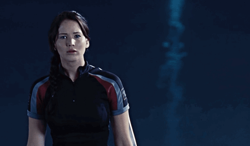 A Woman In A Black Shirt With The Word Hunger Games On Her Sleeve GIF