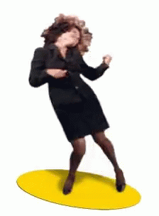 A Woman In A Black Suit And Skirt Is Dancing On A Yellow Mat . GIF