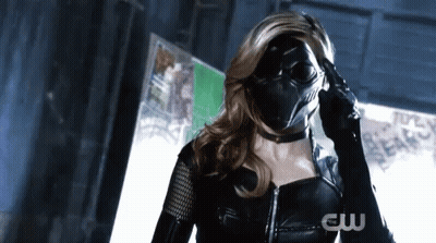 A Woman In A Black Superhero Costume Is Wearing A Mask And Gloves . GIF