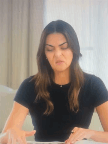 A Woman In A Black T-Shirt Is Making A Funny Face GIF