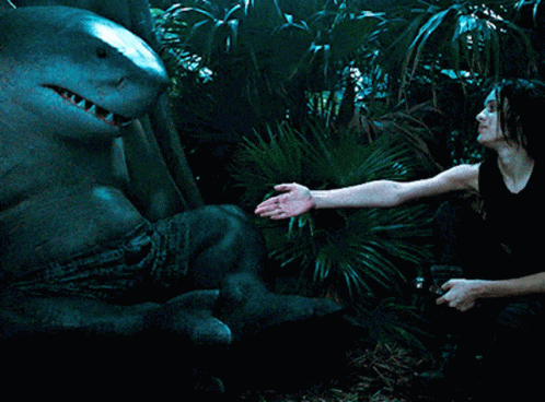 A Woman In A Black Tank Top Is Holding A Shark GIF