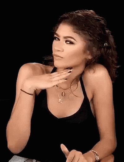 A Woman In A Black Tank Top Is Holding Her Hand To Her Face And Making A Funny Face . GIF