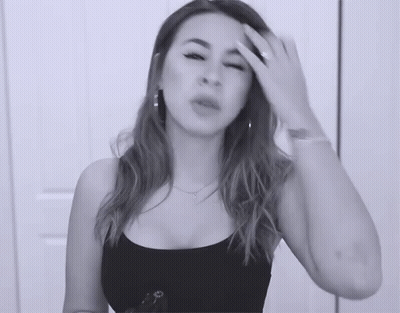 A Woman In A Black Tank Top Is Holding Her Head GIF