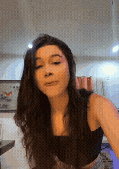 A Woman In A Black Tank Top Is Making A Face GIF