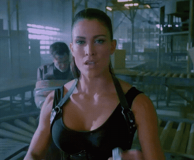 A Woman In A Black Tank Top Is Standing In A Room GIF