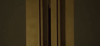 A Woman In A Black Tank Top Is Standing In Front Of A Window . GIF