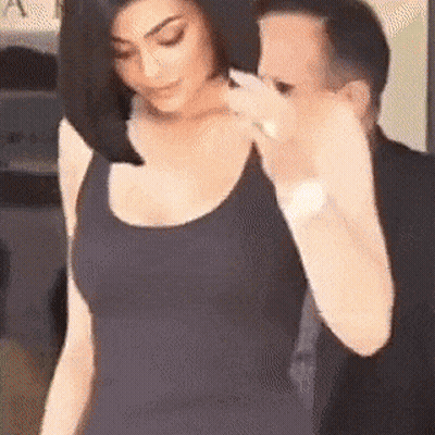A Woman In A Black Tank Top Is Standing Next To A Man In A Black Suit . GIF