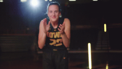 A Woman In A Black Tank Top With The Number 9 On It Is Smiling And Clapping Her Hands GIF