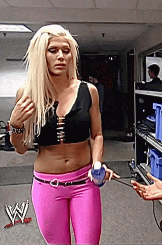 A Woman In A Black Top And Pink Pants Holds A Water Bottle GIF