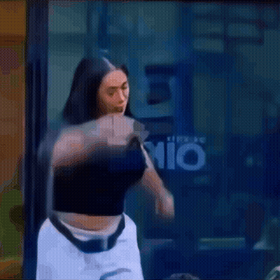 A Woman In A Black Top And White Shorts Is Standing In Front Of A Window With The Letter P On It .. GIF