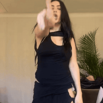 A Woman In A Black Top Is Dancing In A Room GIF