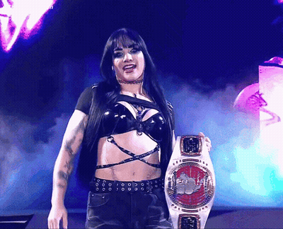 A Woman In A Black Top Is Holding A Belt That Says ' World Heavyweight Champion ' On It GIF