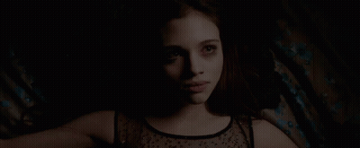 A Woman In A Black Top Is Laying Down In The Dark GIF