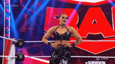 A Woman In A Black Top Is Standing In A Wrestling Ring . GIF