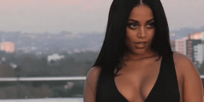 A Woman In A Black Top Is Standing On A Balcony Overlooking The City . GIF