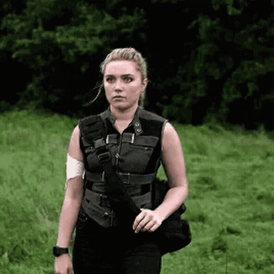 A Woman In A Black Vest Is Standing In A Field . GIF